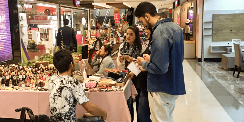 Alunos do curso de cultura UX do Sebrae entrevistando comerciantes no corredor de um shopping em um exercício de pesquisa com usuários.